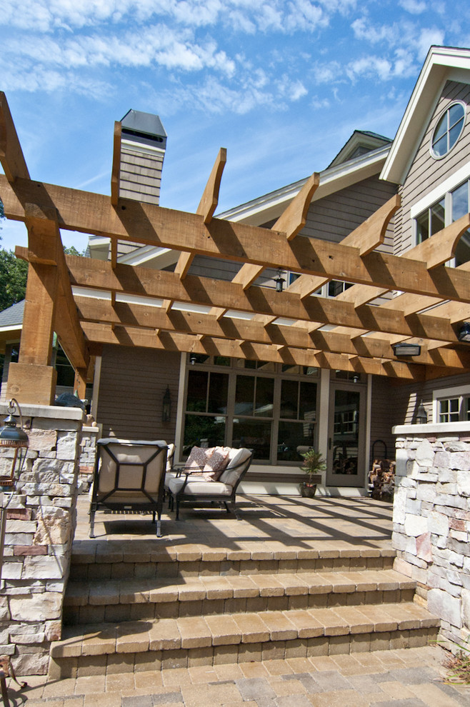 This is an example of a country backyard deck in Grand Rapids with a pergola and an outdoor kitchen.