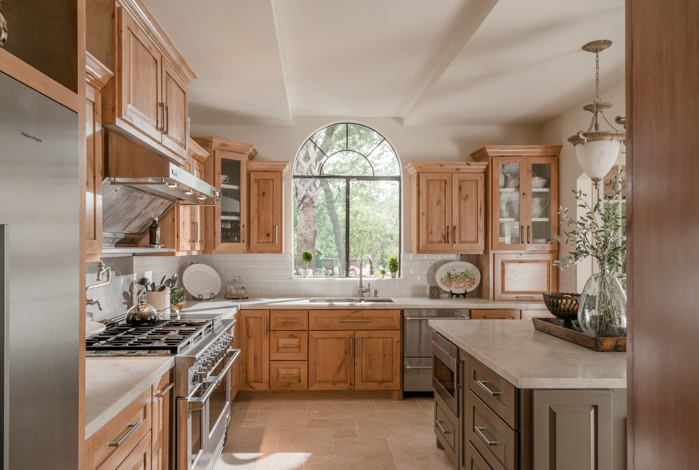Inspiration for a traditional l-shaped open plan kitchen in Houston with a double-bowl sink, raised-panel cabinets, medium wood cabinets, white splashback, subway tile splashback, stainless steel appliances, travertine floors, with island and beige floor.