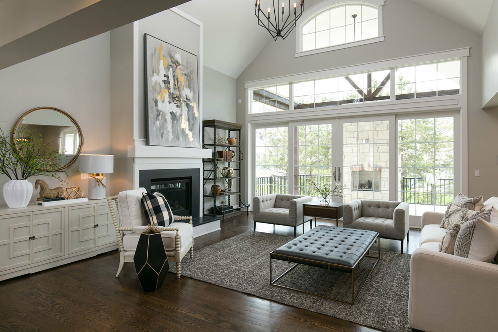 This is an example of a large transitional formal open concept living room in Kansas City with grey walls, a standard fireplace, a wood fireplace surround, no tv, brown floor and dark hardwood floors.