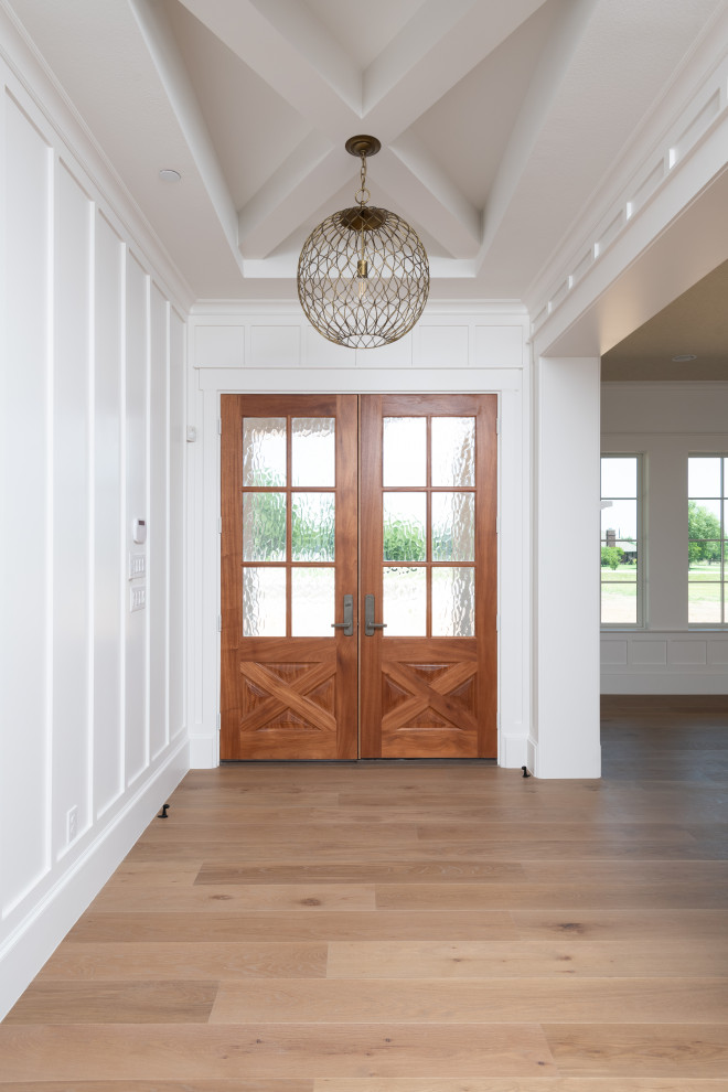 Cette photo montre un hall d'entrée nature de taille moyenne avec un mur blanc, parquet clair, une porte double, une porte en bois brun, un sol marron, poutres apparentes et boiseries.