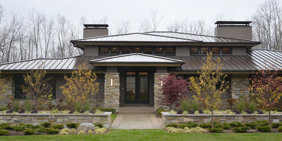 Aménagement d'une façade de maison multicolore moderne de plain-pied avec un revêtement mixte et un toit en métal.