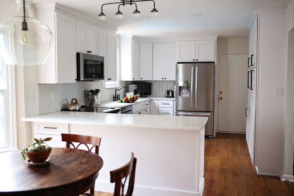 Photo of a mid-sized transitional u-shaped kitchen in DC Metro with an undermount sink, shaker cabinets, white cabinets, quartz benchtops, stainless steel appliances, medium hardwood floors and a peninsula.