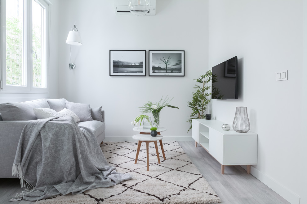 Small scandinavian open concept living room in Madrid with white walls, no fireplace, a wall-mounted tv, grey floor and laminate floors.
