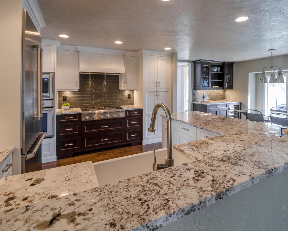 Eat-in kitchen - mid-sized transitional u-shaped medium tone wood floor eat-in kitchen idea in Denver with a farmhouse sink, shaker cabinets, white cabinets, laminate countertops, green backsplash, glass tile backsplash, stainless steel appliances and a peninsula