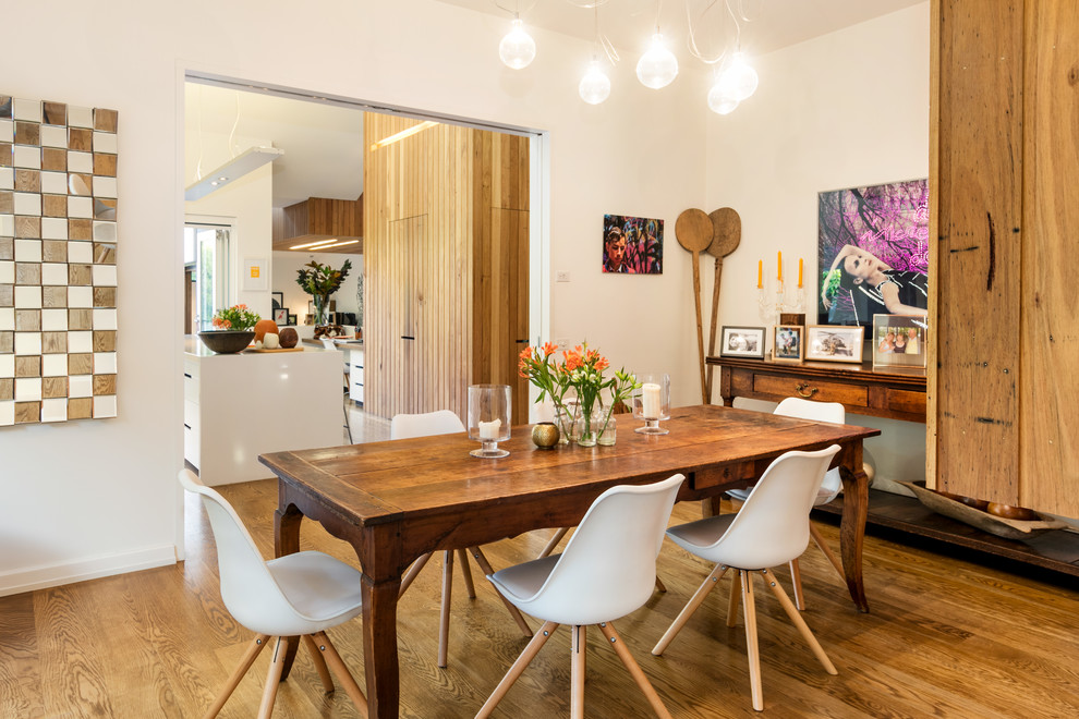 This is an example of a contemporary separate dining room in Melbourne with white walls, medium hardwood floors and brown floor.