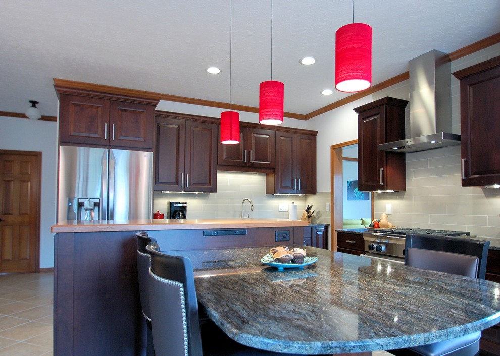 Eat-in kitchen - large transitional l-shaped eat-in kitchen idea in Columbus with an undermount sink, raised-panel cabinets, dark wood cabinets, granite countertops, gray backsplash, ceramic backsplash, stainless steel appliances and an island