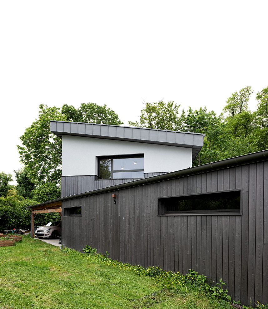 Foto della facciata di una casa ampia grigia contemporanea a due piani con rivestimento in legno, copertura in metallo o lamiera, tetto grigio e pannelli sovrapposti