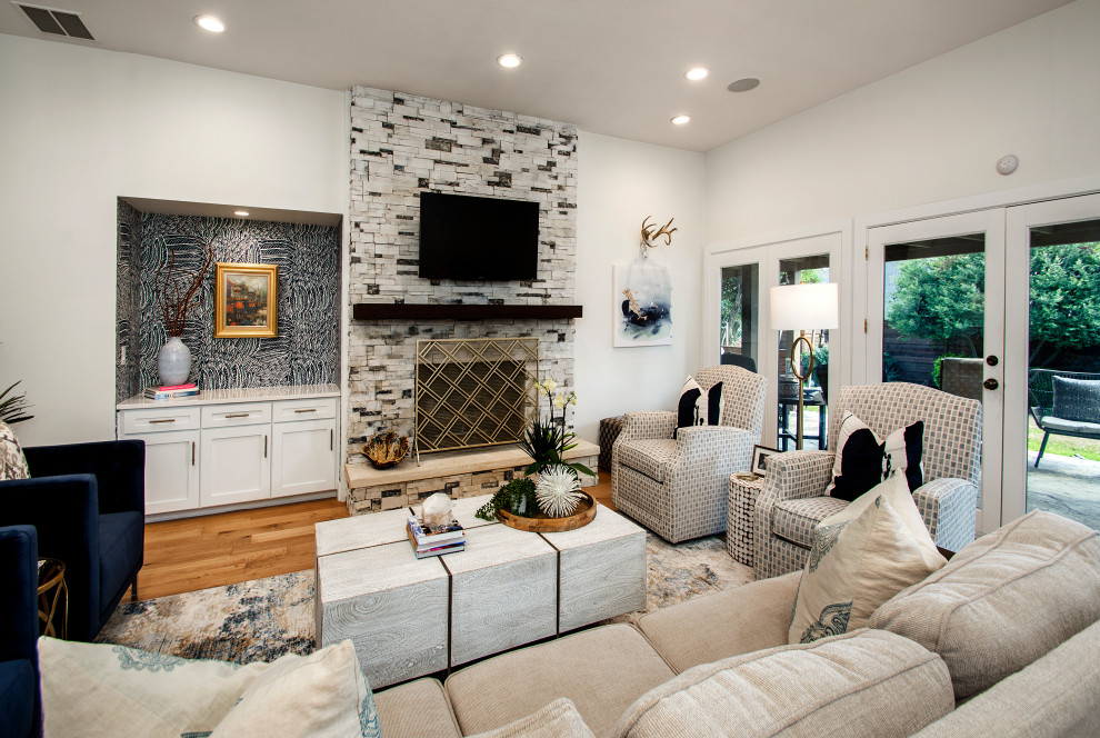 Inspiration for a mid-sized transitional open concept family room in Dallas with white walls, medium hardwood floors, a standard fireplace, a stone fireplace surround, a wall-mounted tv and brown floor.