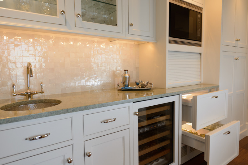 Transitional medium tone wood floor kitchen photo in Boston with a triple-bowl sink, recessed-panel cabinets, white cabinets, granite countertops, white backsplash, mosaic tile backsplash, stainless steel appliances and an island