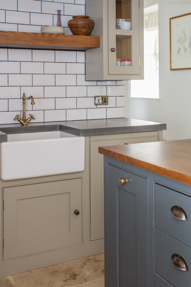 Design ideas for a small traditional l-shaped separate kitchen in Gloucestershire with a farmhouse sink, grey cabinets, concrete benchtops, white splashback, subway tile splashback, stainless steel appliances, limestone floors, with island and beaded inset cabinets.
