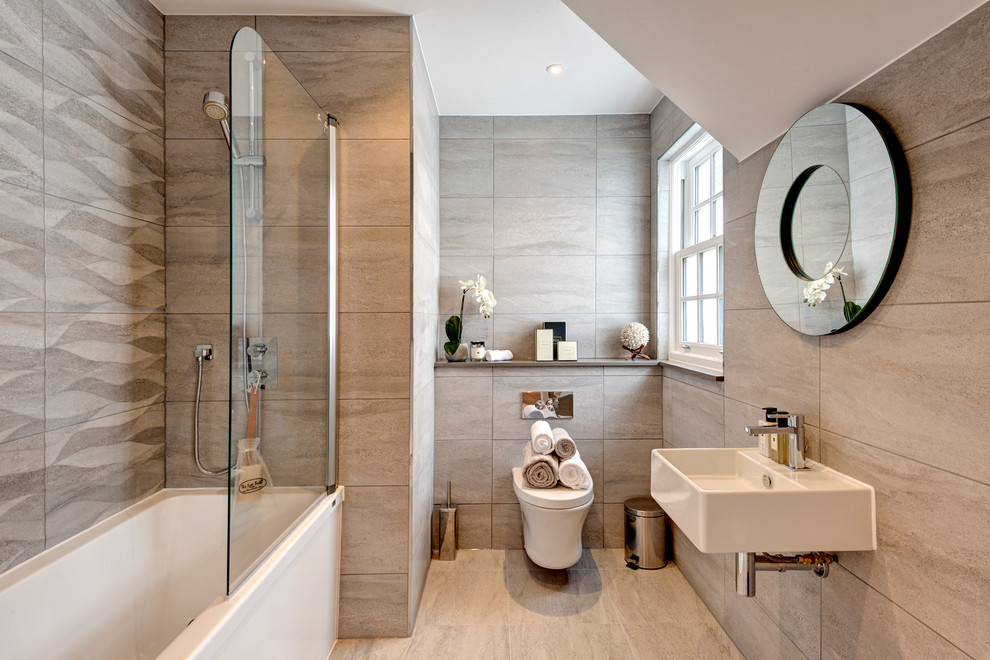 Design ideas for a transitional bathroom in London with a shower/bathtub combo, beige tile, stone slab, a wall-mount sink, an alcove tub and a wall-mount toilet.