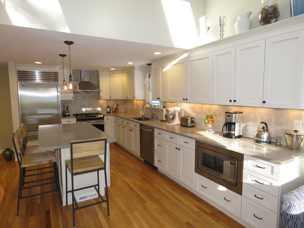 Large transitional l-shaped medium tone wood floor open concept kitchen photo in Boston with an undermount sink, shaker cabinets, white cabinets, quartz countertops, gray backsplash, stainless steel appliances and an island