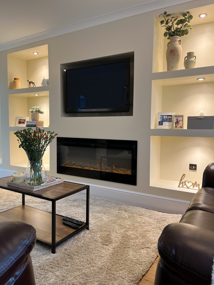 This is an example of a medium sized contemporary formal enclosed living room feature wall in Other with beige walls, light hardwood flooring, a standard fireplace, a plastered fireplace surround, a built-in media unit and brown floors.