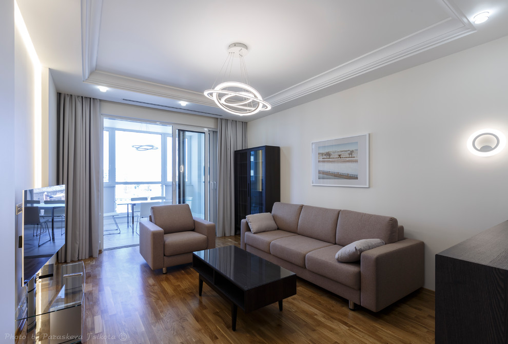 На фото: открытая гостиная комната среднего размера в современном стиле с бежевыми стенами, паркетным полом среднего тона, отдельно стоящим телевизором и коричневым полом с
