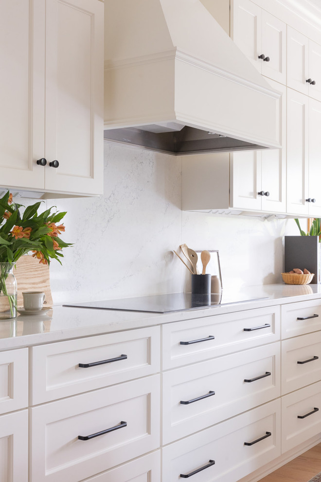 Large transitional light wood floor eat-in kitchen photo with an undermount sink, shaker cabinets, white cabinets, quartz countertops, white backsplash, quartz backsplash, stainless steel appliances, an island and white countertops