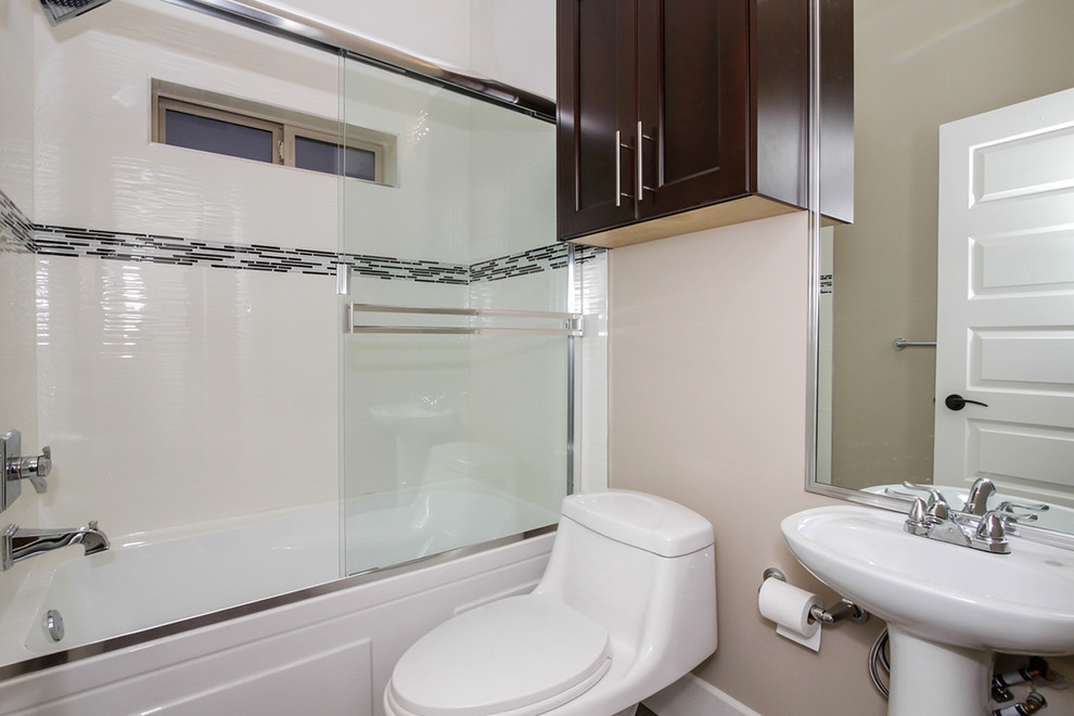 Photo of a mid-sized traditional 3/4 bathroom in Vancouver with a wall-mount sink, recessed-panel cabinets, dark wood cabinets, an alcove tub, an alcove shower, a one-piece toilet, multi-coloured tile and beige walls.