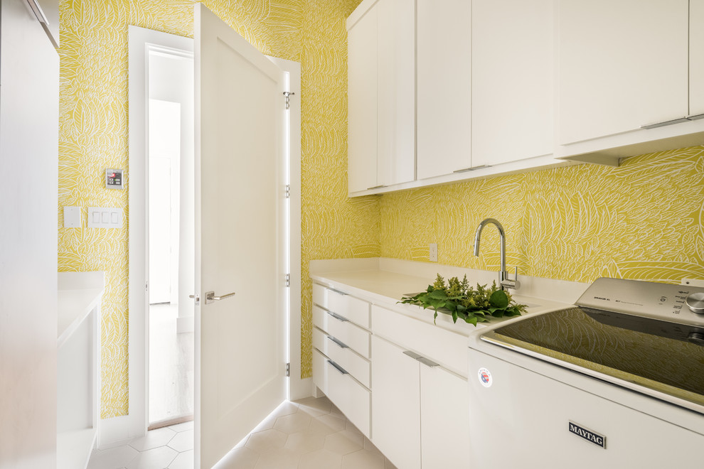 Photo of a contemporary galley dedicated laundry room in Dallas with an undermount sink, flat-panel cabinets, white cabinets, quartz benchtops, yellow walls, porcelain floors, a side-by-side washer and dryer, white floor and white benchtop.