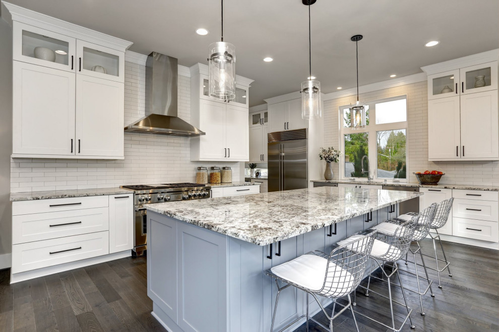 Design ideas for a transitional l-shaped kitchen in Baltimore with an undermount sink, shaker cabinets, white cabinets, white splashback, stainless steel appliances, dark hardwood floors, with island, brown floor and grey benchtop.
