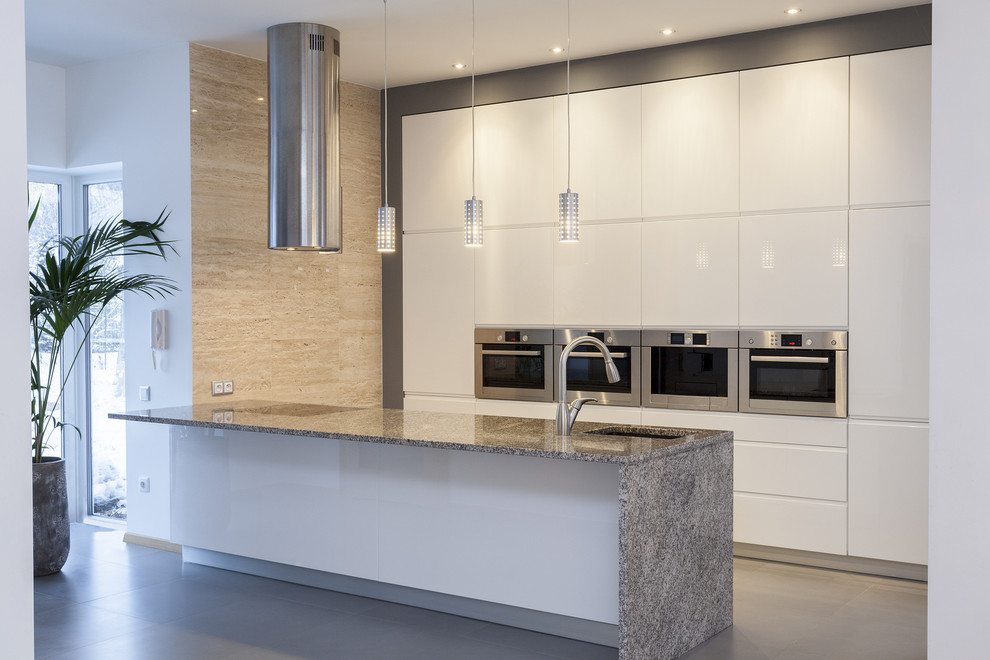 This is an example of a contemporary galley kitchen in DC Metro with an undermount sink, flat-panel cabinets, white cabinets, stainless steel appliances and a peninsula.