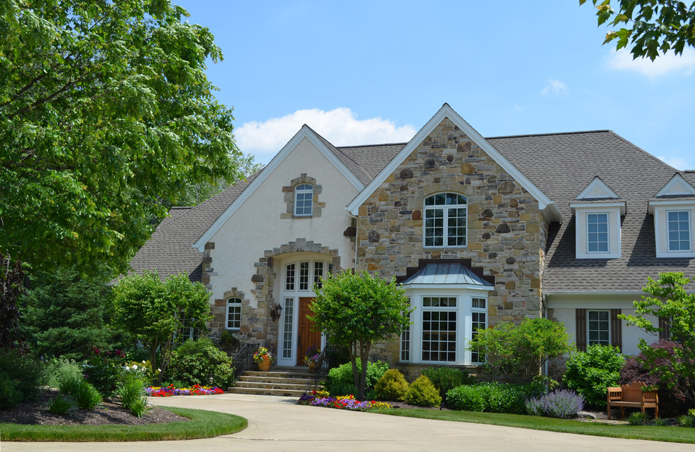 Photo of a large country two-storey stucco beige exterior in Cleveland.