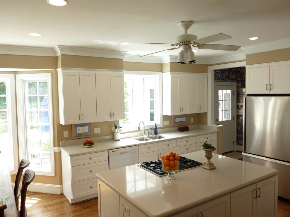 Aménagement d'une cuisine classique avec un placard à porte shaker, des portes de placard blanches et un électroménager en acier inoxydable.