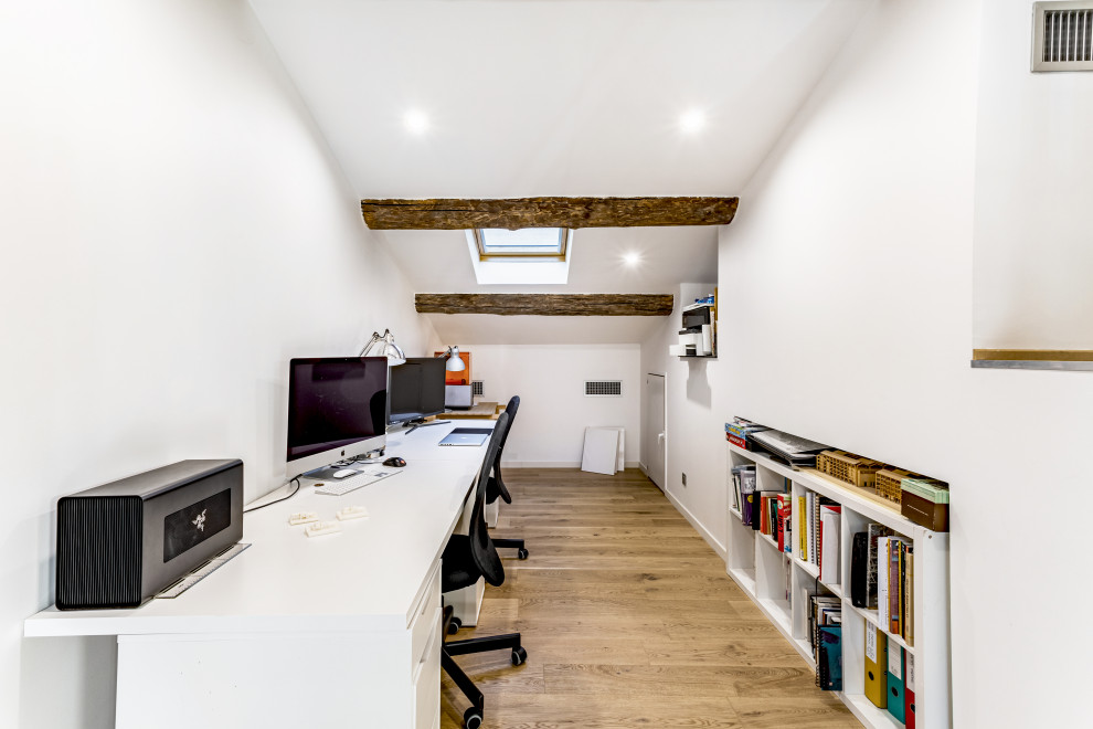 Foto di un ufficio minimal con pareti bianche, parquet chiaro, scrivania autoportante, pavimento beige e travi a vista