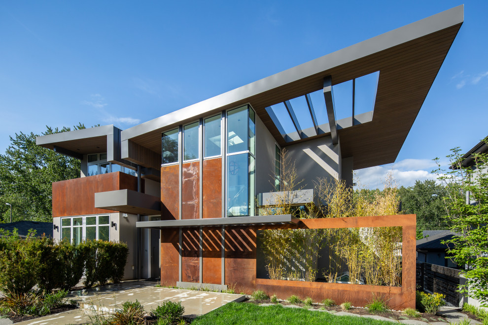Immagine della villa grande marrone moderna a due piani con rivestimento in metallo, tetto a farfalla, copertura in metallo o lamiera e tetto grigio