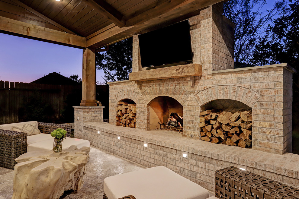 Mid-sized country backyard patio in Houston with with fireplace, concrete slab and a roof extension.