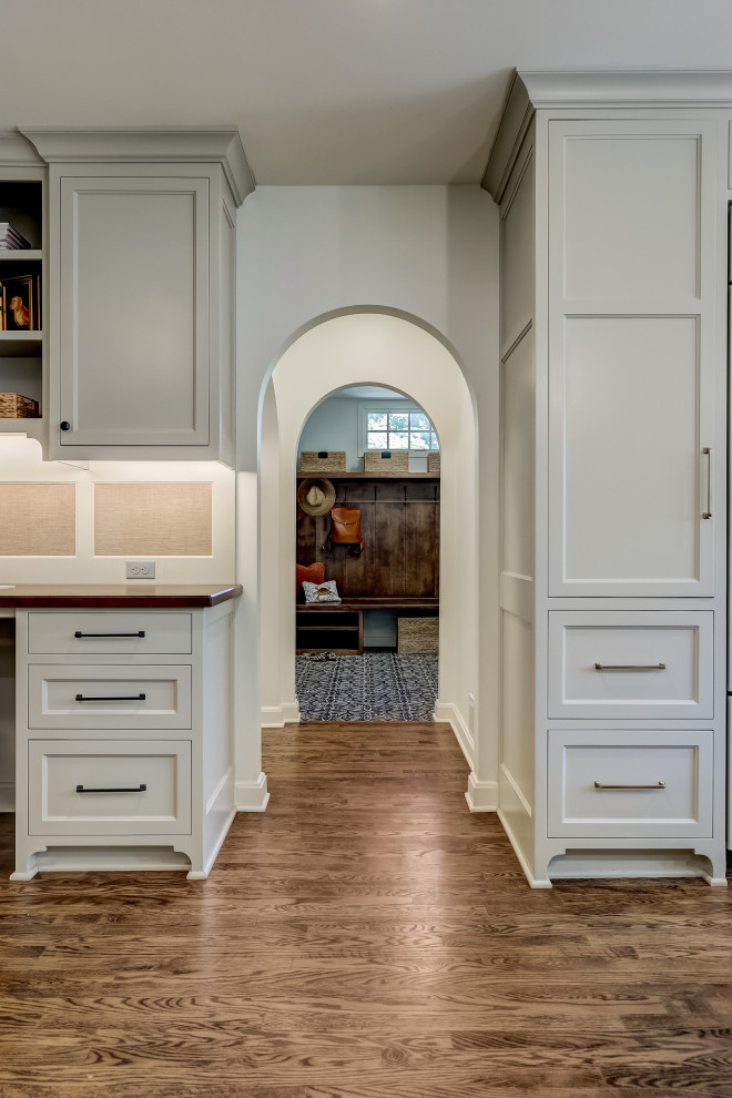 Mid-sized transitional l-shaped medium tone wood floor and brown floor enclosed kitchen photo in Milwaukee with an undermount sink, recessed-panel cabinets, medium tone wood cabinets, quartz countertops, white backsplash, ceramic backsplash, stainless steel appliances, an island and white countertops