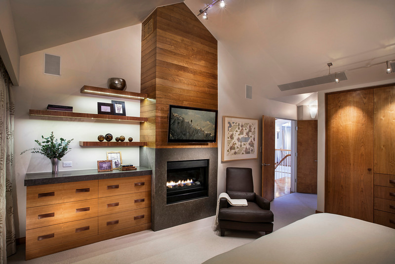 This is an example of a mid-sized contemporary master bedroom in Denver with white walls, carpet, a standard fireplace, a stone fireplace surround and beige floor.