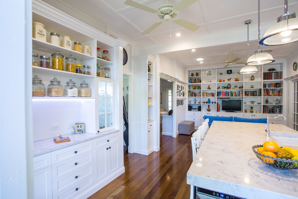 Photo of a large traditional galley eat-in kitchen in Brisbane with shaker cabinets, white cabinets, white splashback, coloured appliances, with island, a farmhouse sink, solid surface benchtops, subway tile splashback and dark hardwood floors.