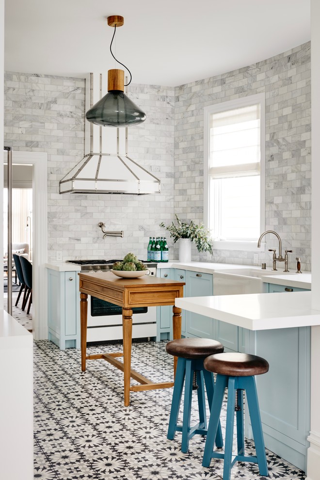 Design ideas for a transitional u-shaped kitchen in San Francisco with a farmhouse sink, shaker cabinets, blue cabinets, grey splashback, marble splashback, white appliances, with island, multi-coloured floor and white benchtop.