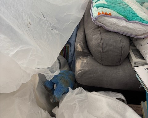 Construction dust on couch and blankets after being covered with plastic for renovation