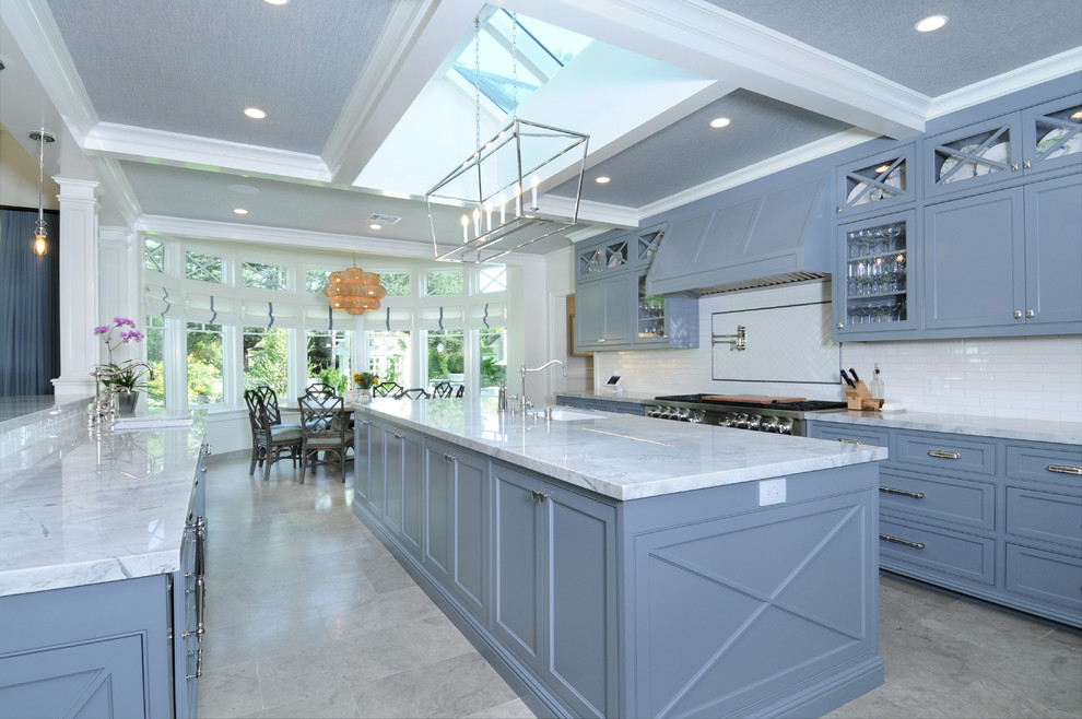 Photo of a traditional u-shaped kitchen in Los Angeles with an undermount sink, beaded inset cabinets, blue cabinets, white splashback, subway tile splashback, stainless steel appliances, with island, grey floor and white benchtop.