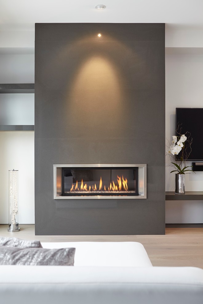 Inspiration for a mid-sized contemporary open concept family room in Toronto with white walls, light hardwood floors, a standard fireplace, a stone fireplace surround and a wall-mounted tv.