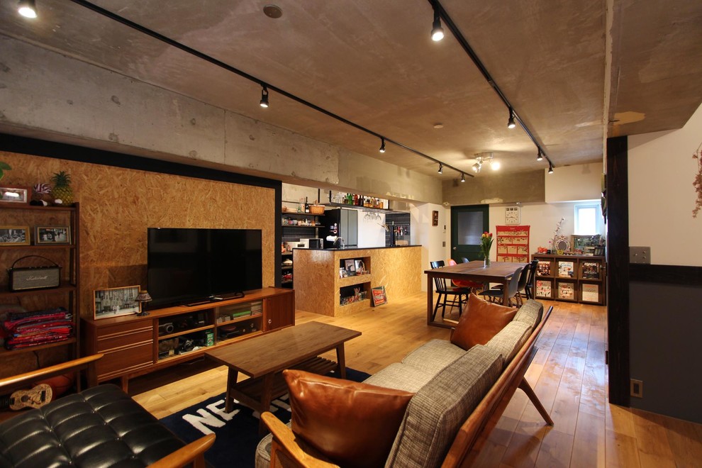 Photo of an industrial family room in Tokyo with white walls, medium hardwood floors, a freestanding tv and brown floor.