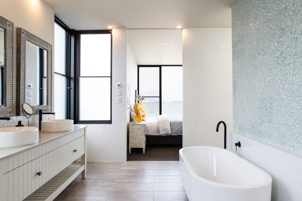 Contemporary master bathroom in Other with a freestanding tub, white walls, cement tiles, a vessel sink, a double vanity, a freestanding vanity, flat-panel cabinets, white cabinets, blue tile, mosaic tile, grey floor and grey benchtops.