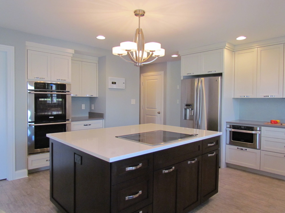 Inspiration for a transitional l-shaped porcelain tile eat-in kitchen remodel in Chicago with a farmhouse sink, shaker cabinets, white cabinets, quartz countertops, blue backsplash, glass tile backsplash, stainless steel appliances and an island
