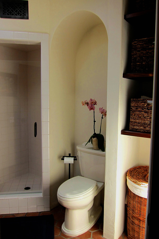 Inspiration for a small mediterranean master bathroom in Santa Barbara with a two-piece toilet, white walls, terra-cotta floors, a corner shower, white tile, ceramic tile, a pedestal sink, open cabinets, dark wood cabinets and red floor.