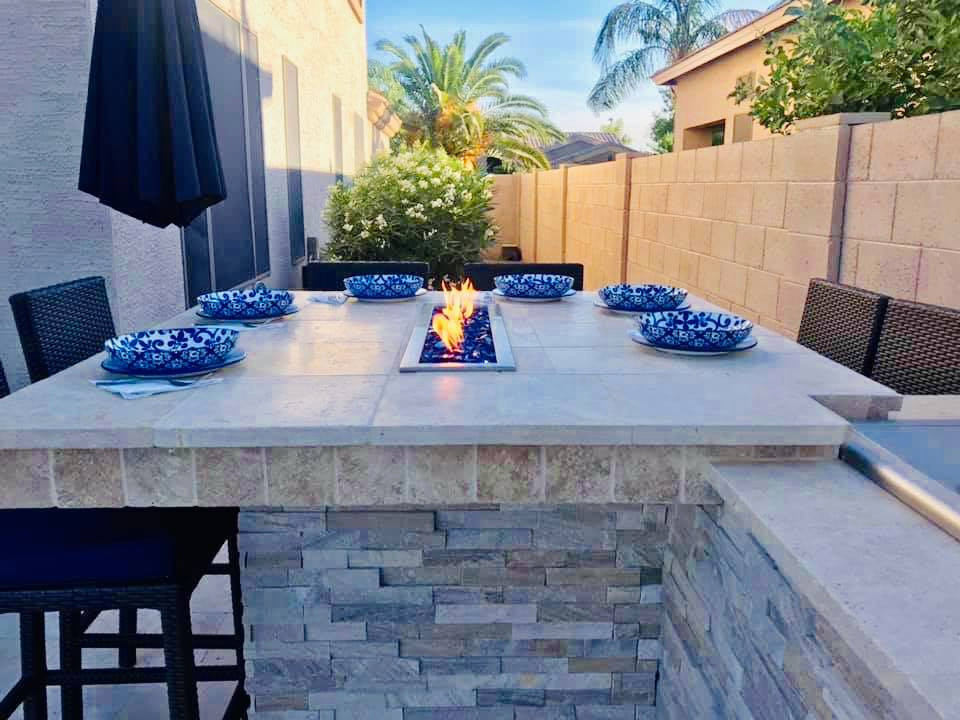 Large modern back patio in Phoenix with a fire feature and brick paving.