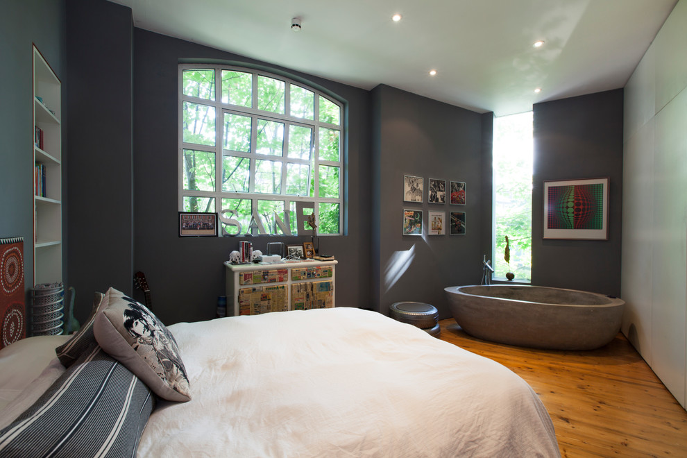 This is an example of a mid-sized eclectic guest bedroom in London with grey walls and medium hardwood floors.