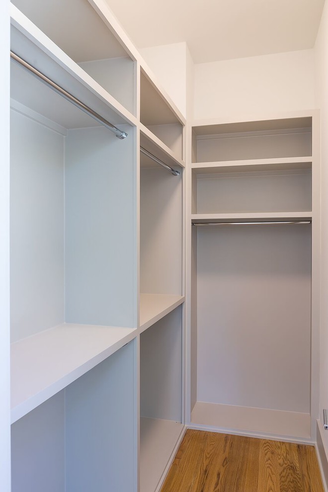 Inspiration for a mid-sized contemporary gender-neutral walk-in wardrobe in Houston with open cabinets, white cabinets and medium hardwood floors.