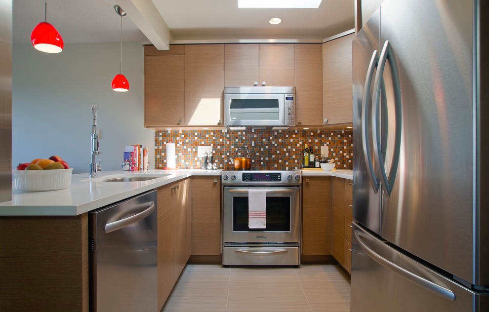 This is an example of a contemporary u-shaped kitchen in Vancouver with multi-coloured splashback, mosaic tile splashback, stainless steel appliances, light wood cabinets, flat-panel cabinets and an undermount sink.