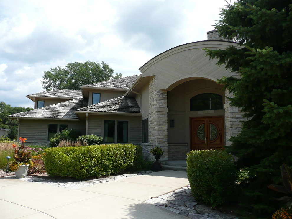 Large contemporary two-storey beige exterior in Other with stone veneer and a hip roof.