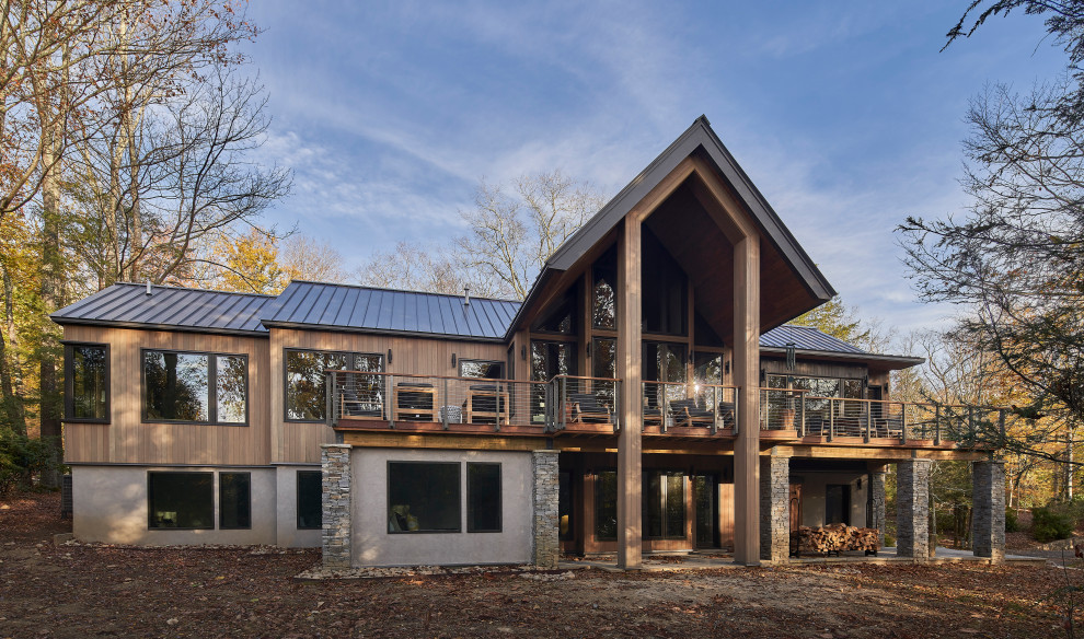 Example of a large mountain style beige two-story wood and board and batten gable roof design with a metal roof and a gray roof
