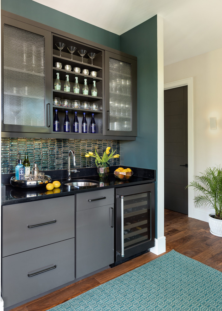 Inspiration for a transitional single-wall wet bar in Miami with an undermount sink, flat-panel cabinets, grey cabinets, green splashback, dark hardwood floors and black benchtop.