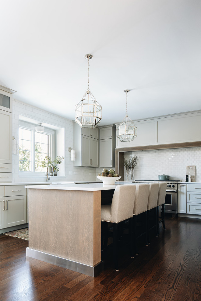 Inspiration for a mid-sized transitional dark wood floor eat-in kitchen remodel in Chicago with a farmhouse sink, shaker cabinets, gray cabinets, quartz countertops, white backsplash, ceramic backsplash, paneled appliances, an island and white countertops