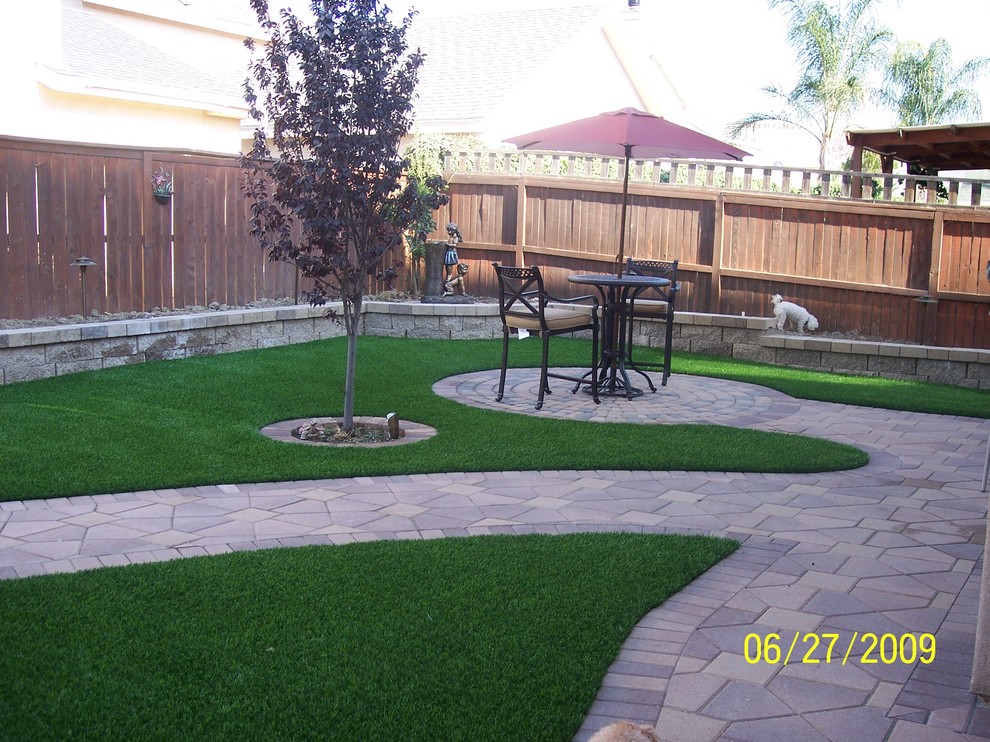 This is an example of a large traditional backyard xeriscape in Orange County with a retaining wall and brick pavers.