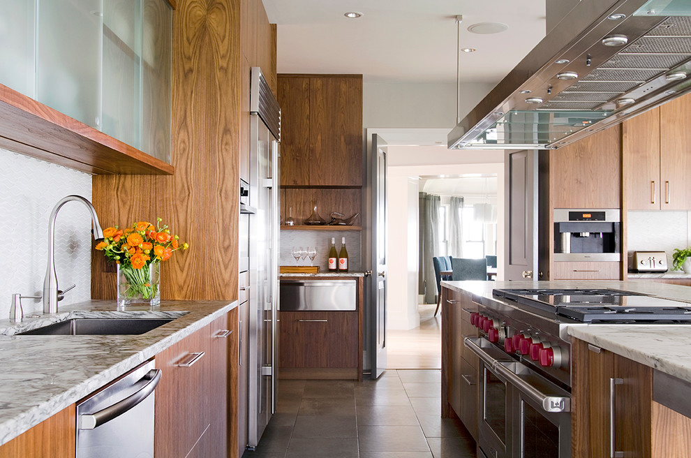 Example of a huge transitional galley slate floor eat-in kitchen design in Boston with an undermount sink, flat-panel cabinets, dark wood cabinets, recycled glass countertops, white backsplash, glass tile backsplash, stainless steel appliances and an island