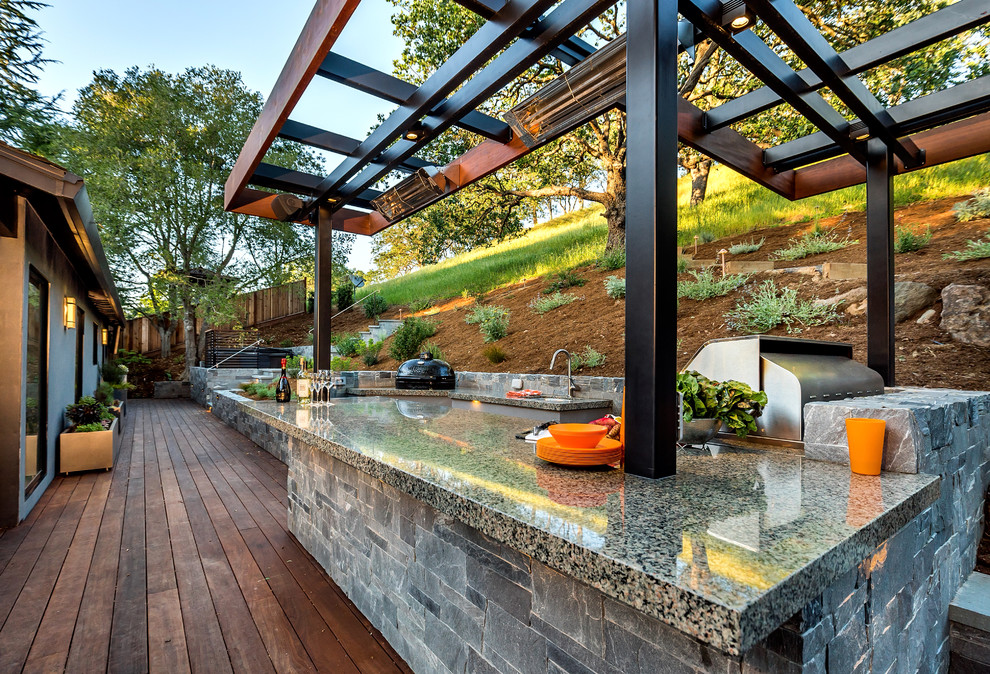 Large midcentury backyard deck in San Francisco with an outdoor kitchen and a pergola.